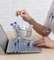 Unrecognizable woman doctor on online consultation for laptop. Online pharmacy concept. Faceless pharmacist puts medicine in a mini shopping cart